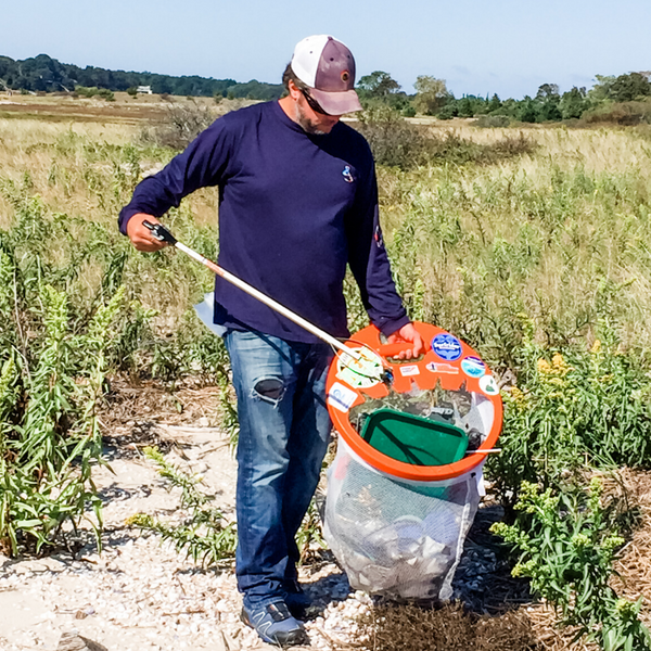 man picking up trash with an orange contraption